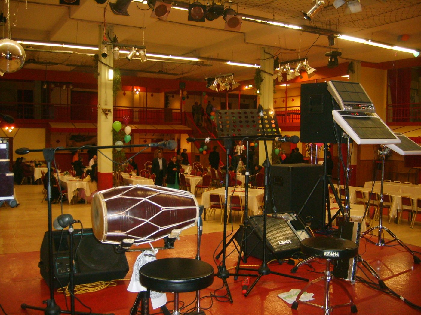 A dholak drum miked up on stage next to electronic Roland drum pads