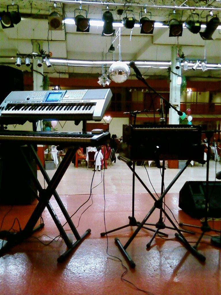 View from behind a keyboard on stage, looking out over an empty hall with a mirror ball