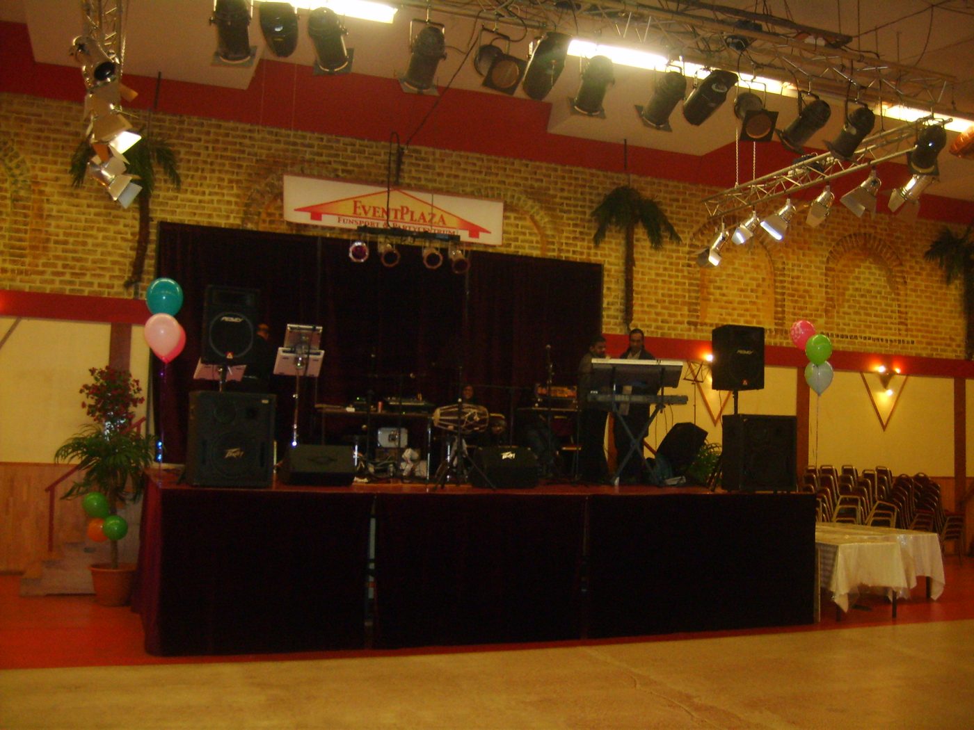 A decorated hall with a stage, stage lighting and balloons before an event