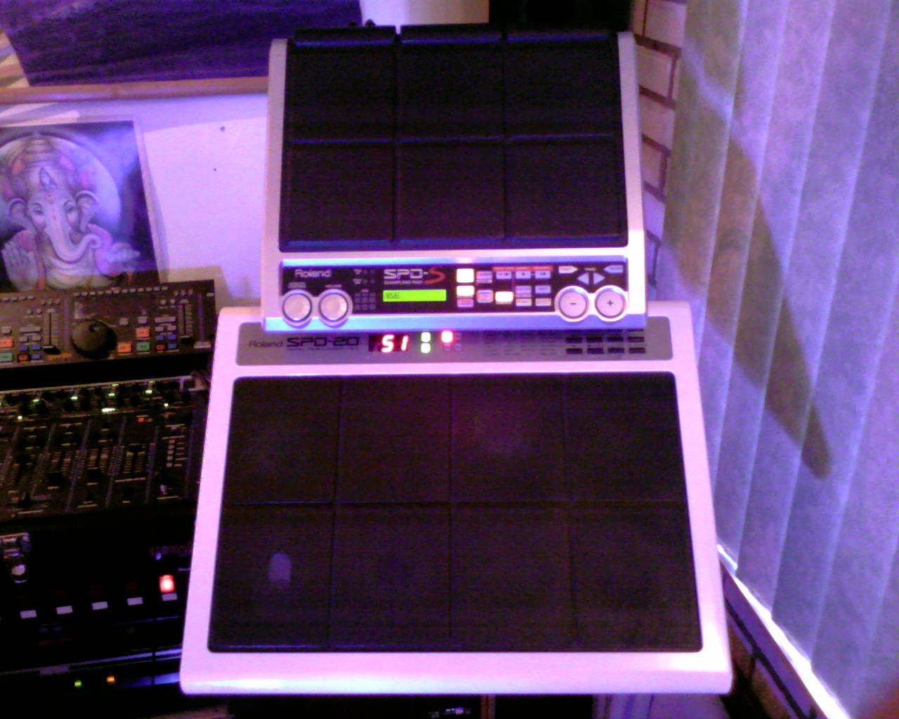 Roland SPD-S and SPD-20 sampling pads lit in purple light, next to a mixing desk